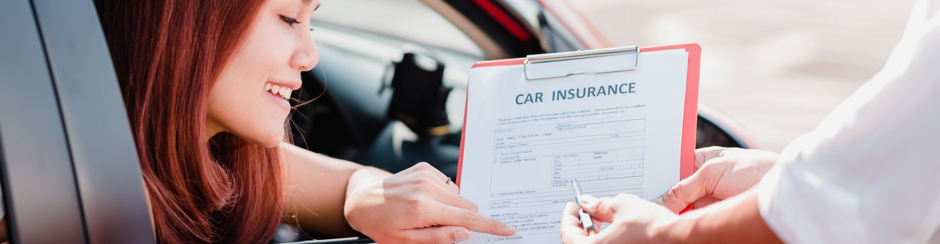 woman in red car pointing at car insurance contract