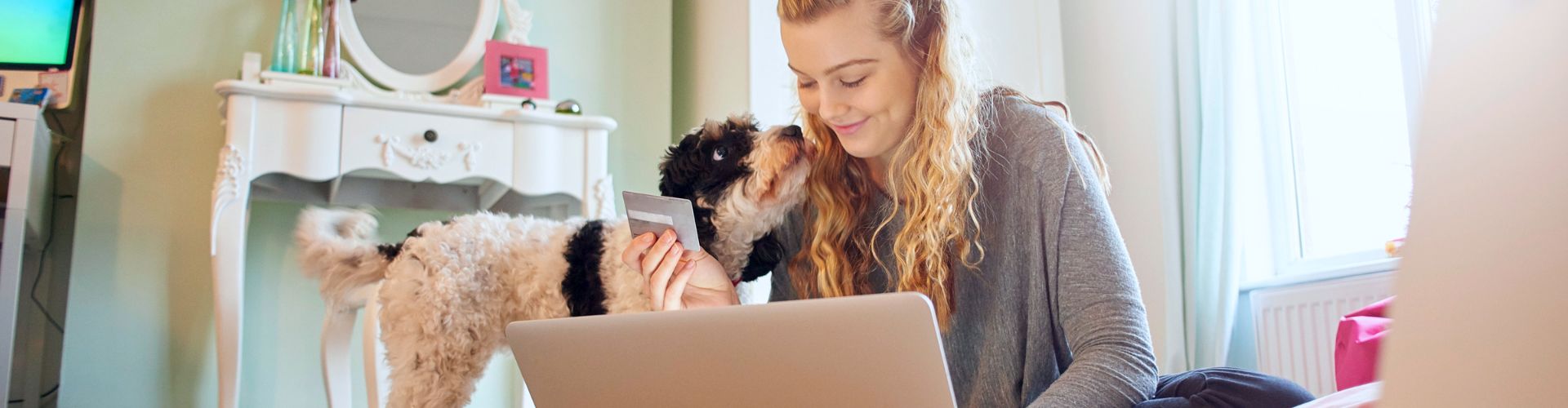 woman and dog looking at laptop holding credit card